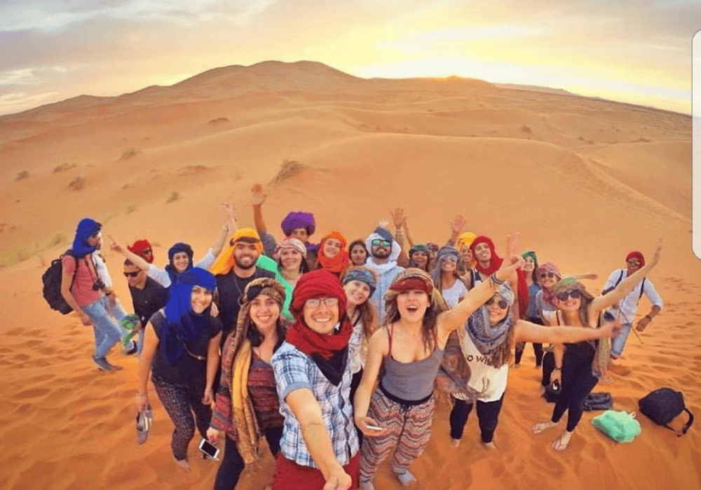 Merzouga Desert Experience Group of travelers enjoying the Sahara dunes in Merzouga during sunset